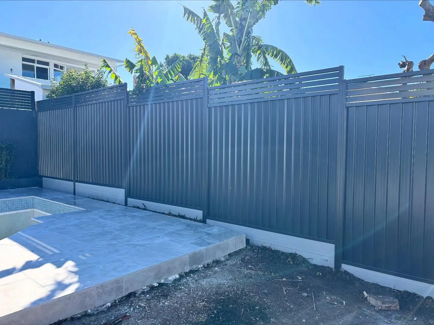 New charcoal Colorbond pool fence with slat top — after