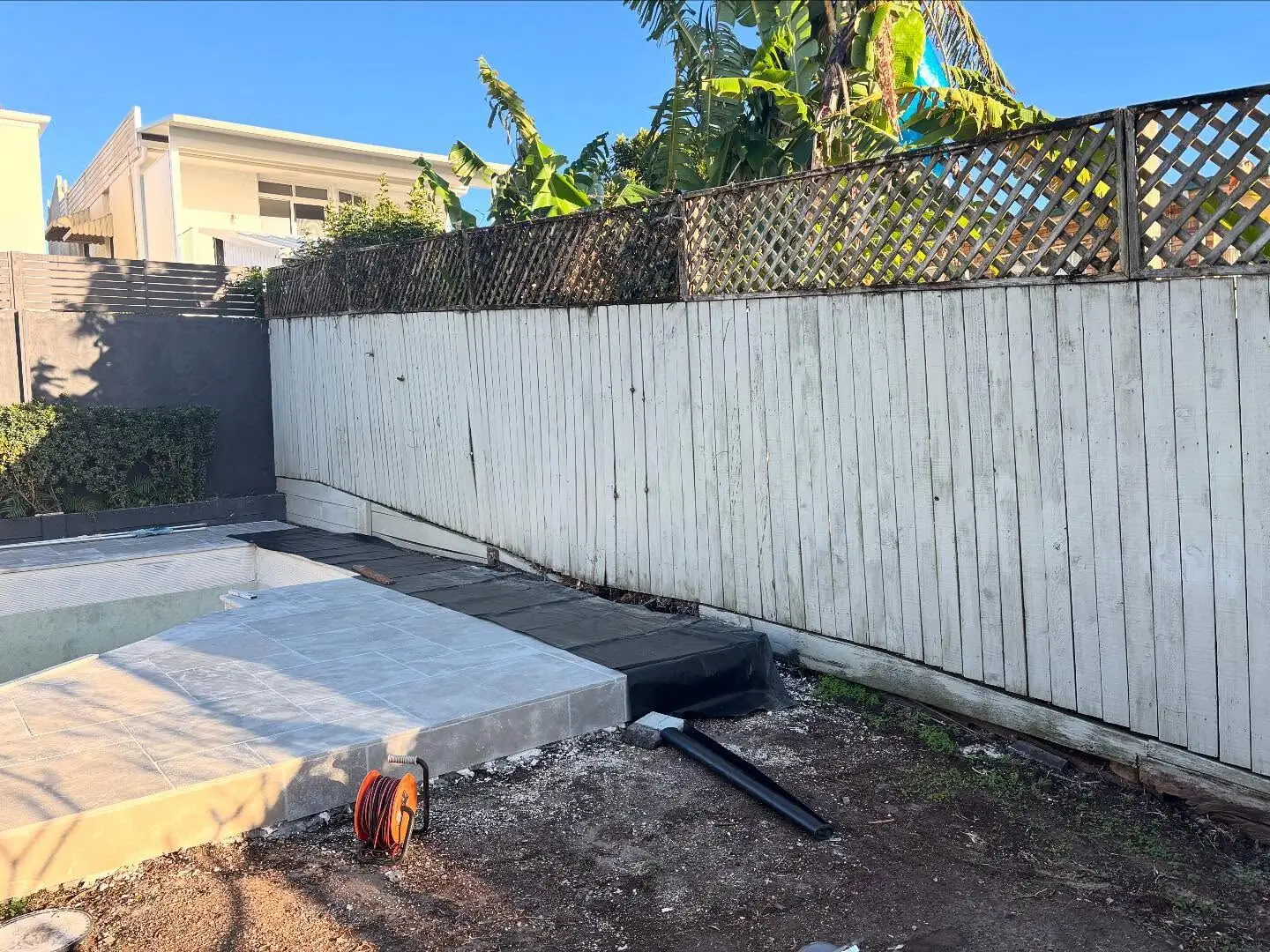 Tired old white paling fence around a pool — before