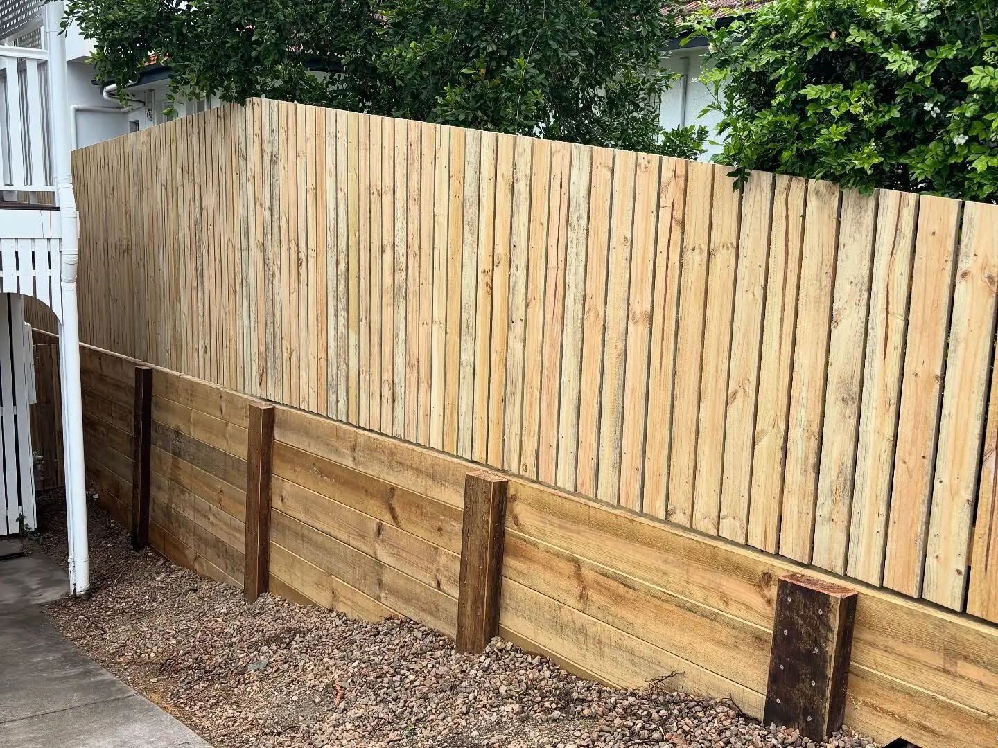 Timber paling fence on top of a hardwood sleeper retaining wall